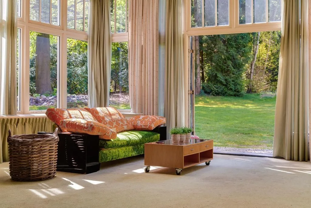 Buitenplaats Benthuys, Baarn: De woonkamer met de hoge ramen naar de tuin