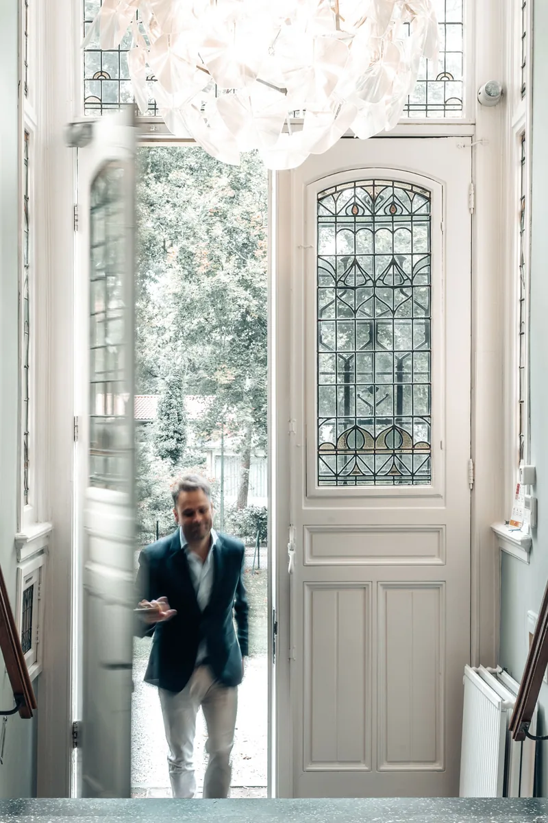 Jan-Willem Andriessen, founder & owner van redres., loopt door een monumentale voordeur met glas-in-lood naar binnen