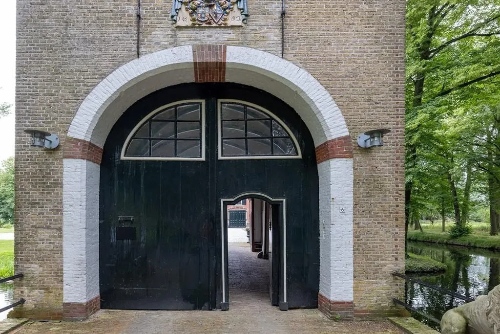 Poortgebouw van Epema State in Ysbrechtum: een wit omlijste rondboog met groene deuren in een bakstenen gevel