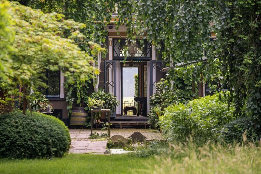 Vanuit de tuin van Landhuis Oosterhouw in Leens kijk je door de openstaande deuren dwars door het huis naar het licht aan de andere kant